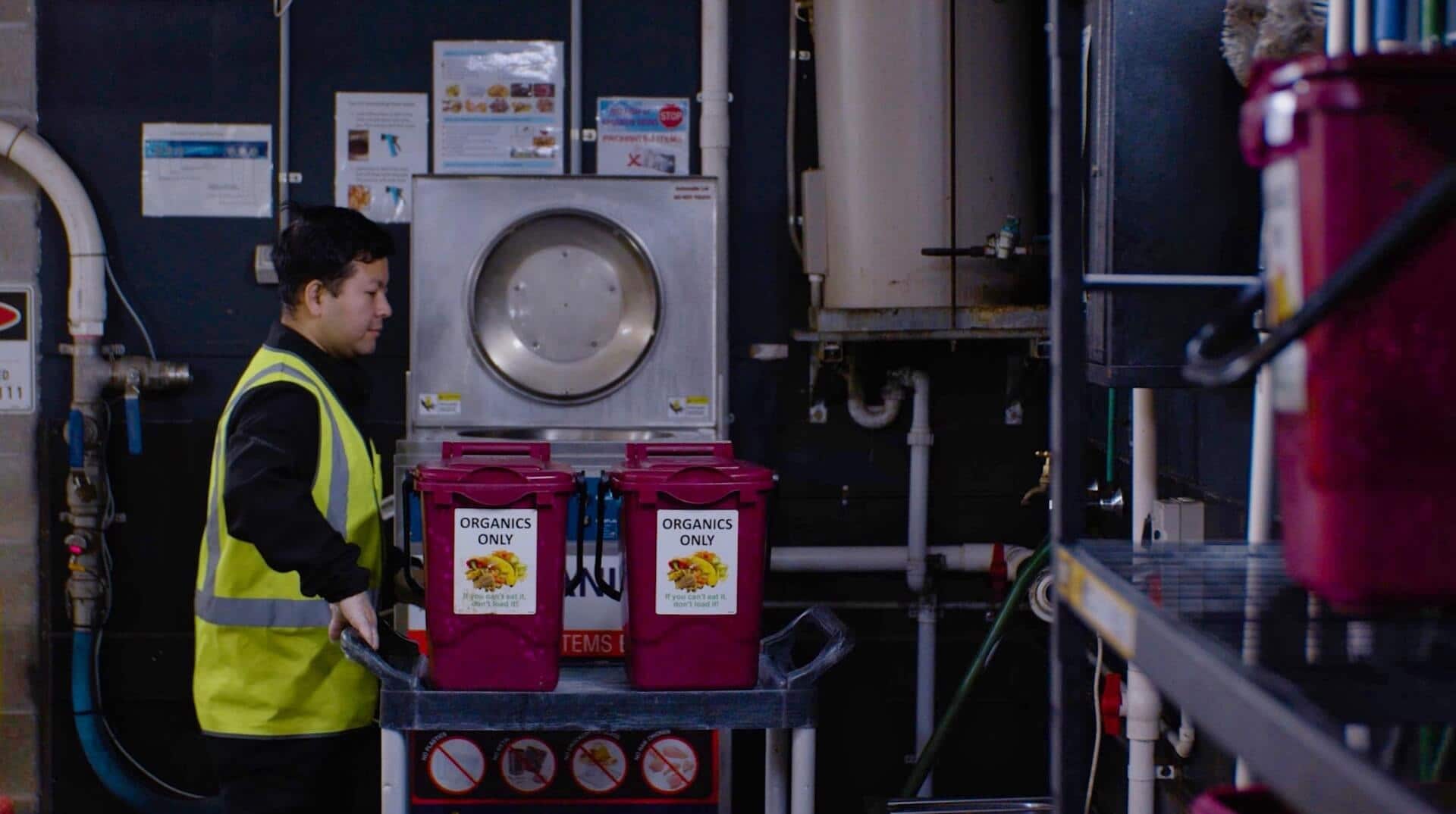 Kitchen worker moving food waste caddies on a trolley